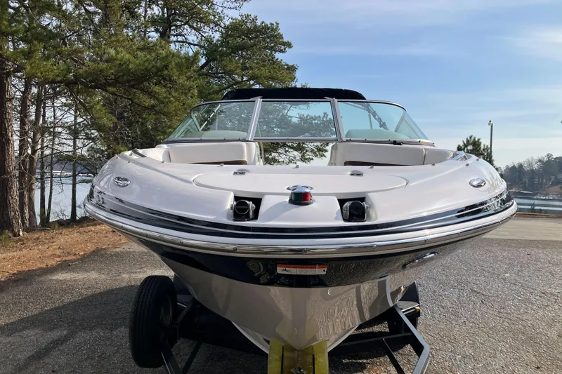 Slide: The Image of 2006 Four Winns 240 Horizon boat on trailer, surrounded by trees and lake view. - 4