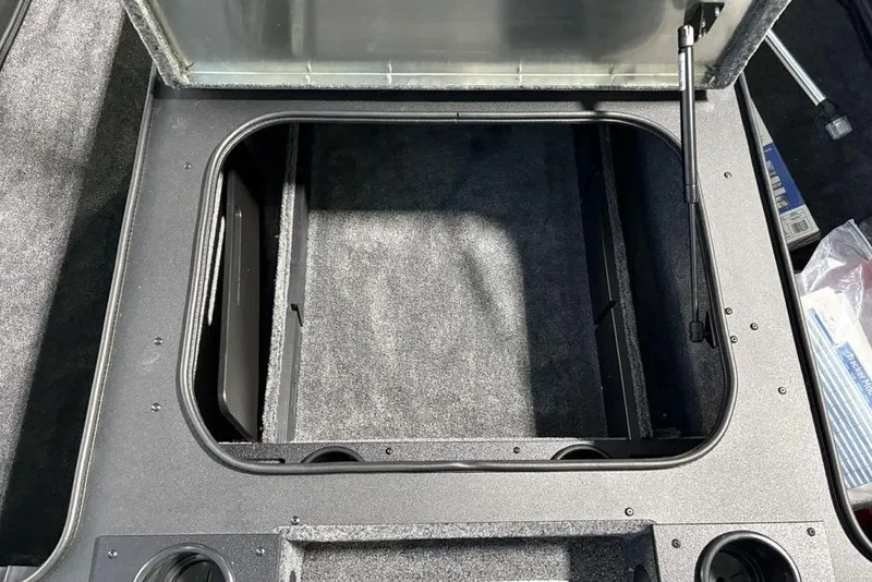 Slide: The Image of Open storage compartment in 2026 Tracker Pro Team 175 boat, featuring carpeted interior. - 12