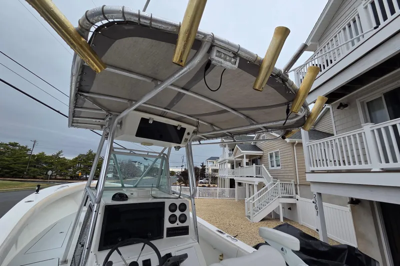 Slide: The Image of 1996 Regulator 26 Classic boat with T-top and rod holders, docked near coastal homes. - 12