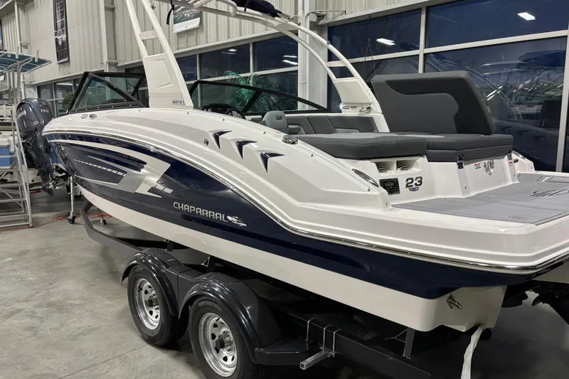 Slide: The Image of 2026 Chaparral 23 SSi boat in showroom, sleek design, dual-axle trailer. - 5