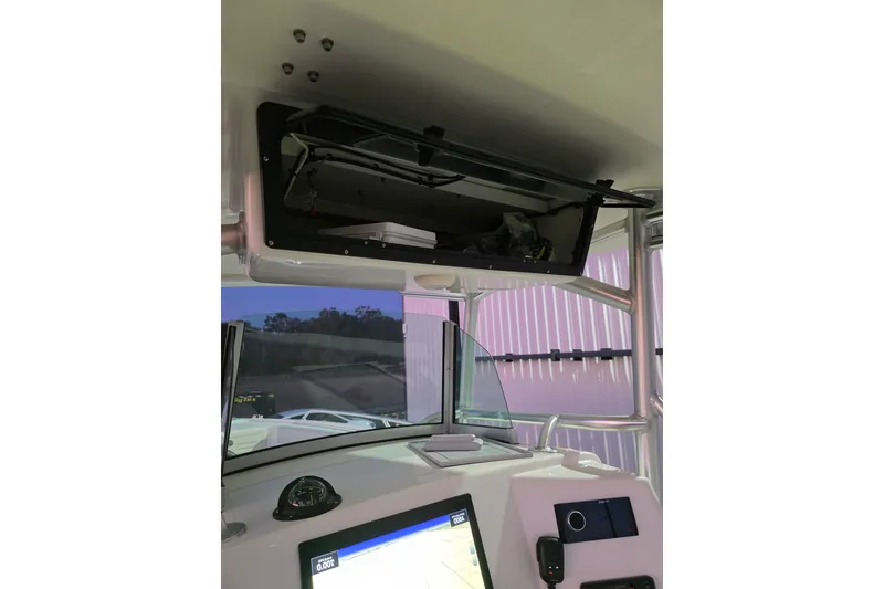 Slide: The Image of 2020 Mako 284 Center Console boat interior with open storage compartment and navigation equipment. - 23