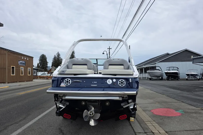 Slide: The Image of 2026 Regal LS6 boat rear view at a marina, showcasing sleek design and dual propellers. - 2