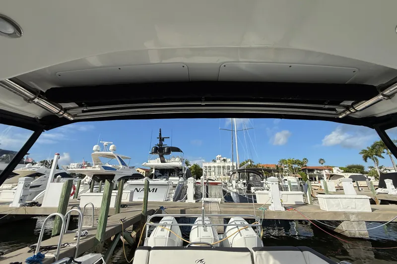 Slide: The Image of 2022 Monterey 385SS Super Sport at marina, surrounded by luxury yachts and clear blue sky. - 49