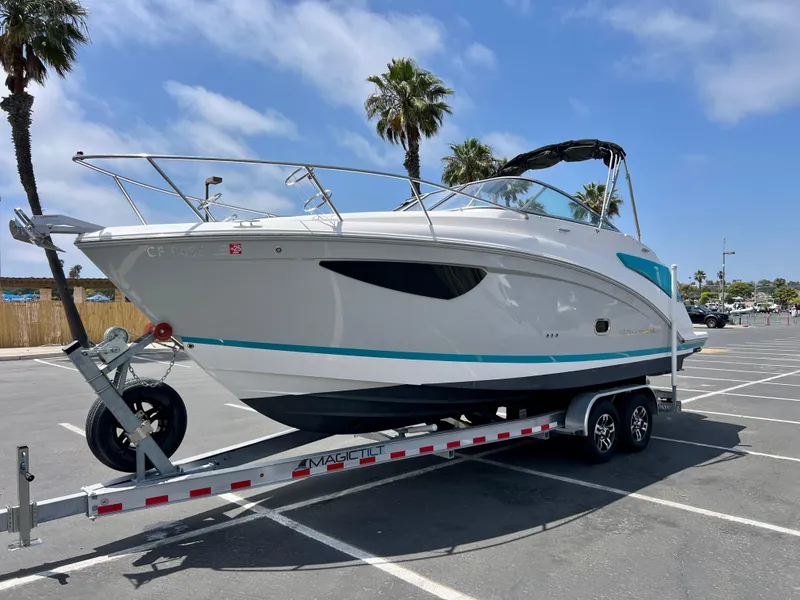 Slide: The Image of 2019 Regal 26 XO boat on trailer in sunny parking lot with palm trees. - 2