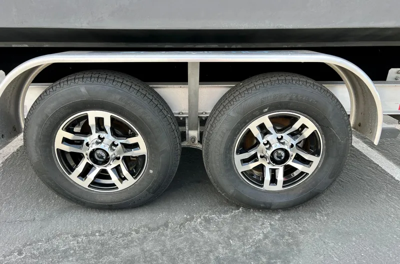 Slide: The Image of Trailer wheels of a 2019 Regal 26 XO boat on pavement. - 22