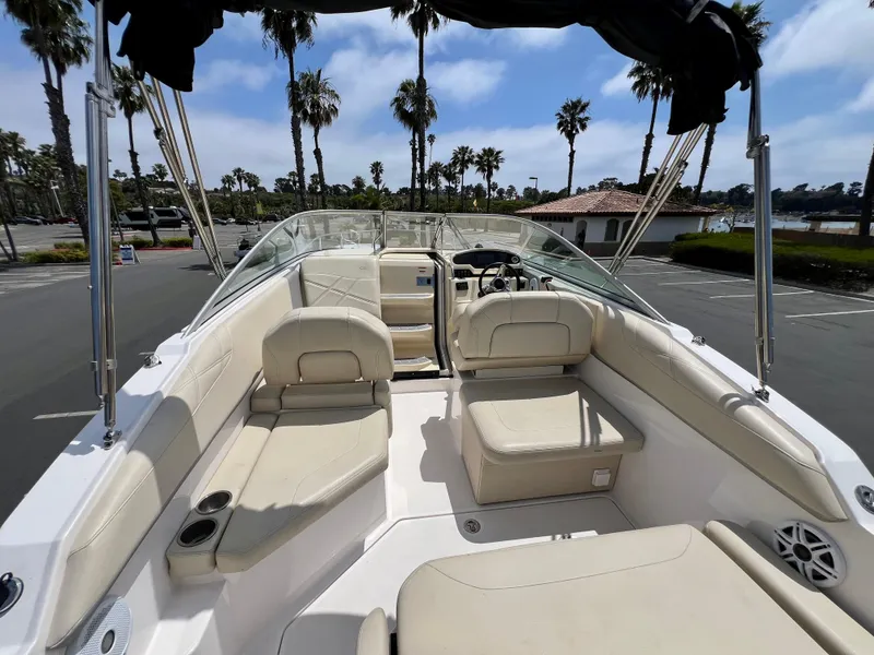 Slide: The Image of 2019 Regal 26 XO boat interior with beige seating, palm trees in background. - 28