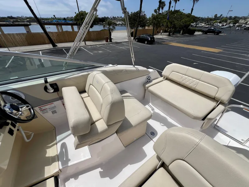 Slide: The Image of 2019 Regal 26 XO boat interior with beige seating, docked near a waterfront. - 33