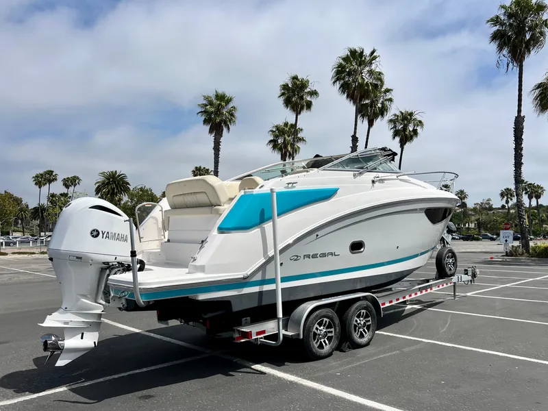 Slide: The Image of 2019 Regal 26 XO boat on trailer, parked in lot with palm trees. - 6