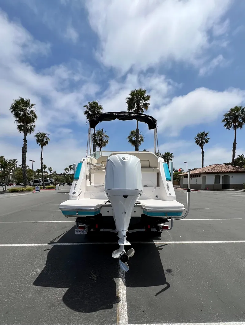 Slide: The Image of 2019 Regal 26 XO boat parked, rear view, with palm trees and cloudy sky background. - 8