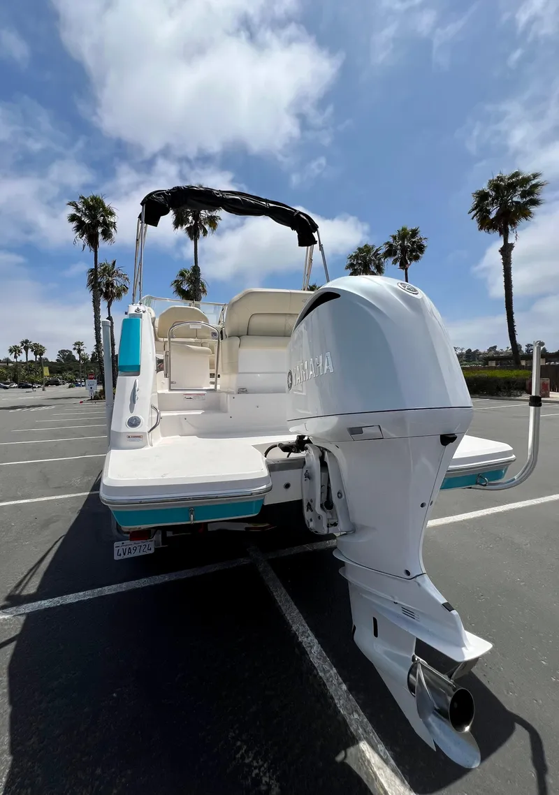Slide: The Image of 2019 Regal 26 XO boat with outboard motor, parked under a sunny sky with palm trees. - 9