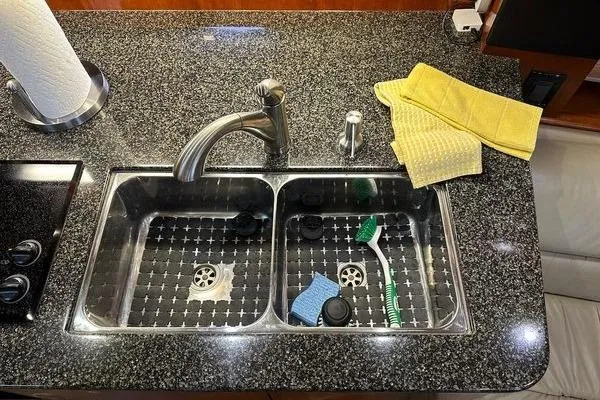 Slide: The Image of Granite countertop with double sink, faucet, and cleaning supplies on a 2005 Cruisers 420 yacht. - 16
