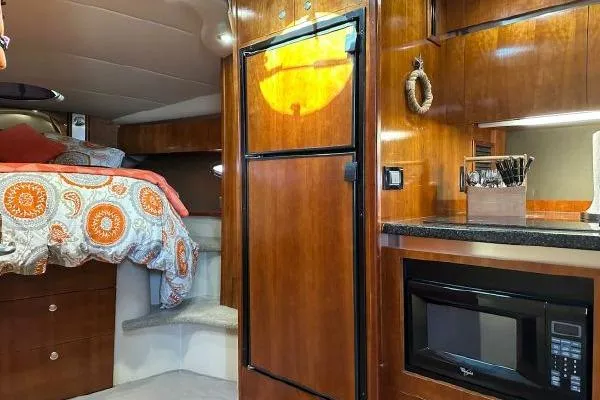 Slide: The Image of Luxurious 2005 Cruisers 420 yacht interior with cozy bed, kitchenette, and wooden cabinetry. - 19