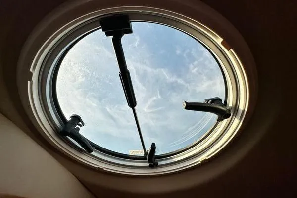 Slide: The Image of Round window view from 2005 Cruisers 420 yacht, showcasing blue sky and clouds. - 61