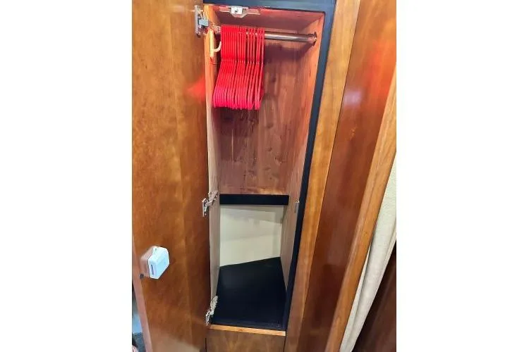 Slide: The Image of Wooden closet with red hangers inside a 2005 Cruisers 420 boat. - 57