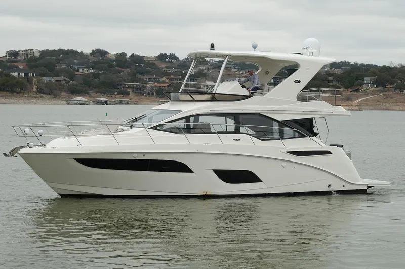 Slide: The Image of 2018 Sea Ray Fly 460 yacht cruising on a calm lake with scenic background. - 10