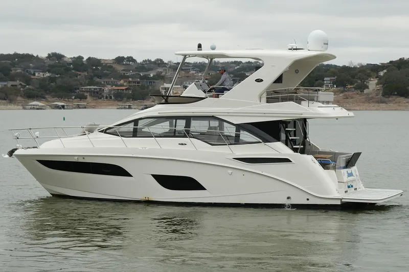 Slide: The Image of 2018 Sea Ray Fly 460 yacht cruising on a calm lake with scenic background. - 11