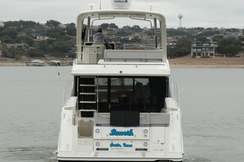 Slide: The Image of 2018 Sea Ray Fly 460 yacht cruising on a lake with scenic shoreline views. - 14