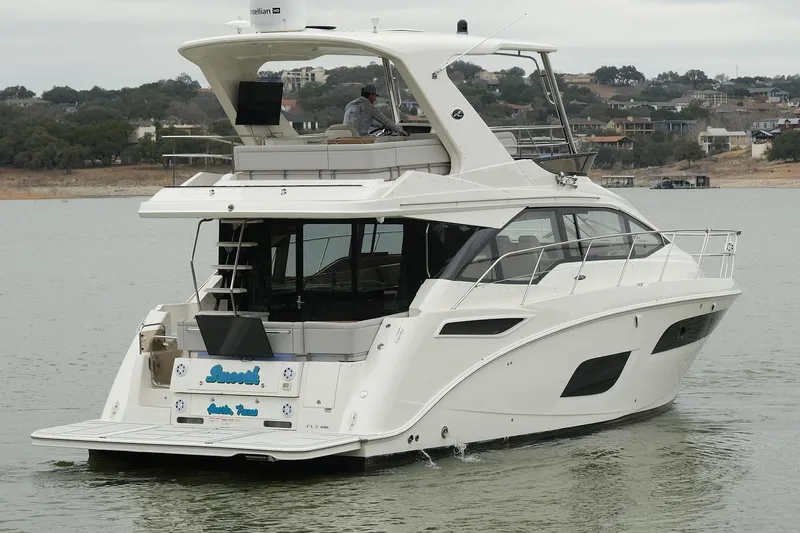 Slide: The Image of 2018 Sea Ray Fly 460 yacht cruising on a calm lake with scenic background. - 15