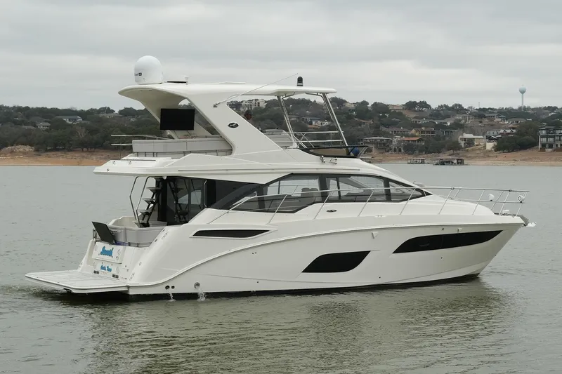 Slide: The Image of 2018 Sea Ray Fly 460 yacht cruising on a calm lake with scenic background. - 16