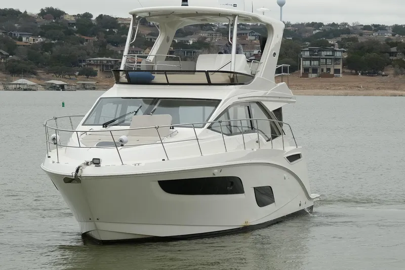 Slide: The Image of 2018 Sea Ray Fly 460 yacht cruising on a calm lake with scenic background. - 18