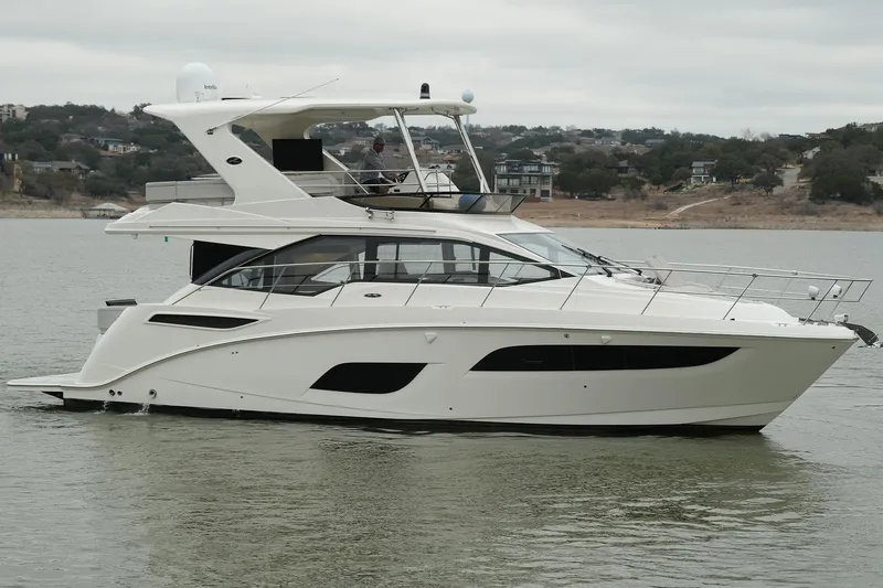 Slide: The Image of 2018 Sea Ray Fly 460 yacht cruising on a calm lake with scenic background. - 2