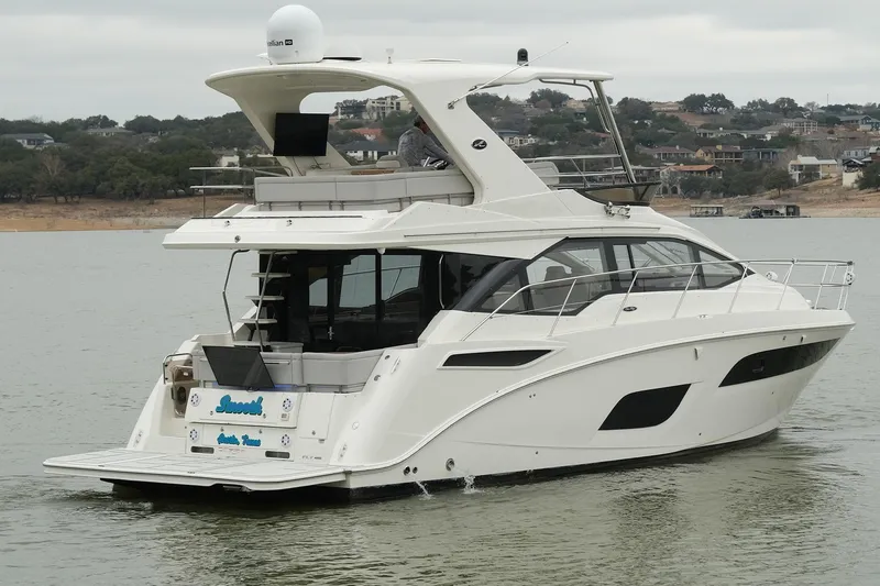 Slide: The Image of 2018 Sea Ray Fly 460 yacht cruising on a calm lake with scenic background. - 20