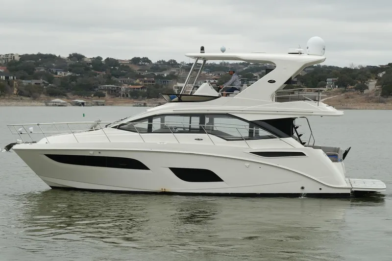 Slide: The Image of 2018 Sea Ray Fly 460 yacht on calm water, with scenic shoreline background. - 3