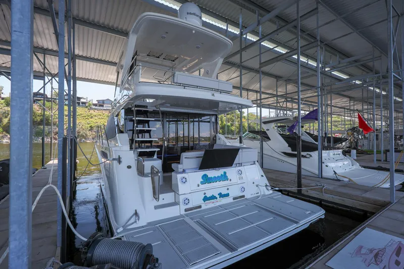 Slide: The Image of 2018 Sea Ray Fly 460 yacht docked in a marina, featuring a sleek design and spacious deck. - 31