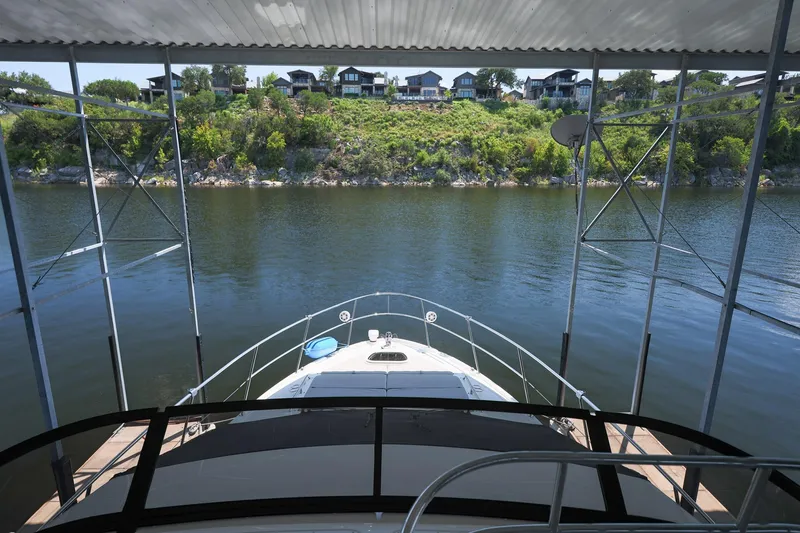 Slide: The Image of 2018 Sea Ray Fly 460 yacht docked, overlooking serene lake and lush greenery. - 52