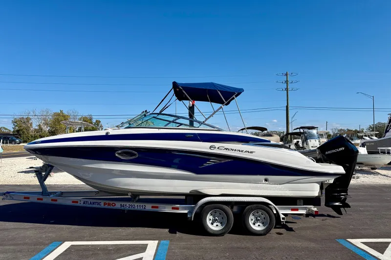 The Image of 2023 Crownline Eclipse E235 XS boat on trailer, blue and white design, parked outdoors. - 0