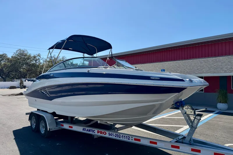 Slide: The Image of 2023 Crownline Eclipse E235 XS boat on trailer, parked outdoors under clear sky. - 4