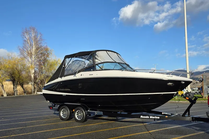 The Image of 2026 Regal LS4C boat on trailer in parking lot, clear sky background. - 0