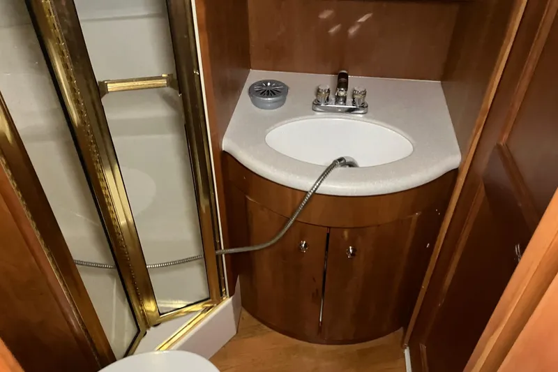 Slide: The Image of 2002 Silverton 39 Motor Yacht bathroom with shower, sink, and wooden cabinetry. - 43