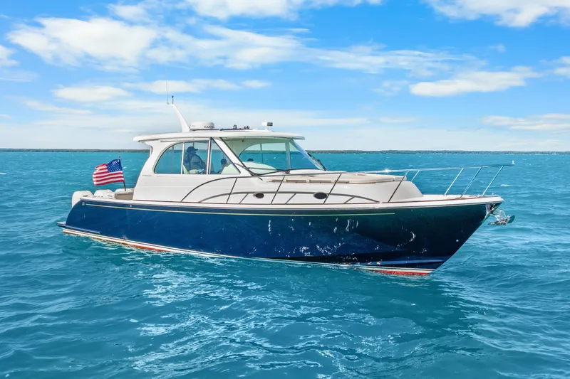 The Image of 2021 Hinckley Sport Boat 40 X cruising on clear blue water under a sunny sky. - 1