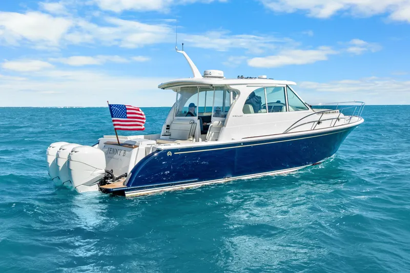 Slide: The Image of 2021 Hinckley Sport Boat 40 X cruising on open water under a clear sky. - 10
