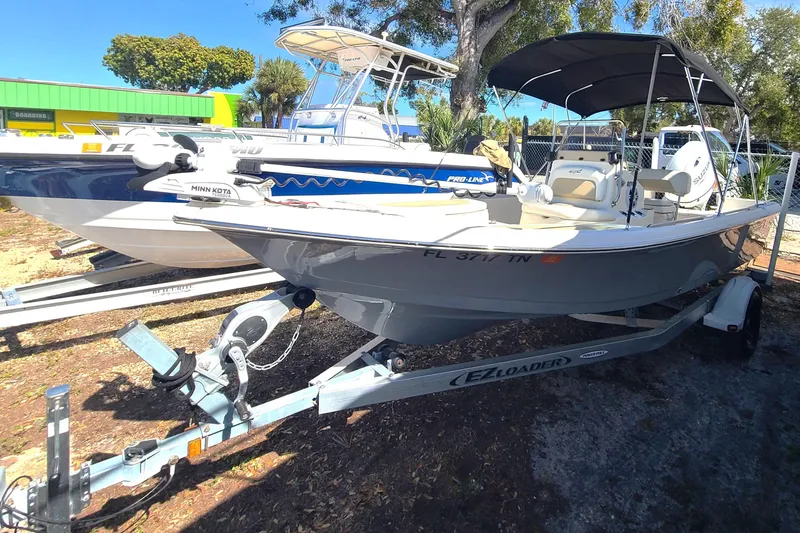 Slide: The Image of 2023 Bulls Bay 2000 boat on trailer, parked outdoors with canopy and Minn Kota motor. - 1