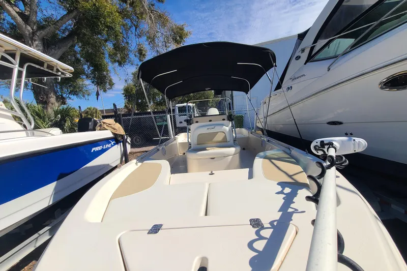 Slide: The Image of 2023 Bulls Bay 2000 boat with canopy, docked between other vessels. - 9