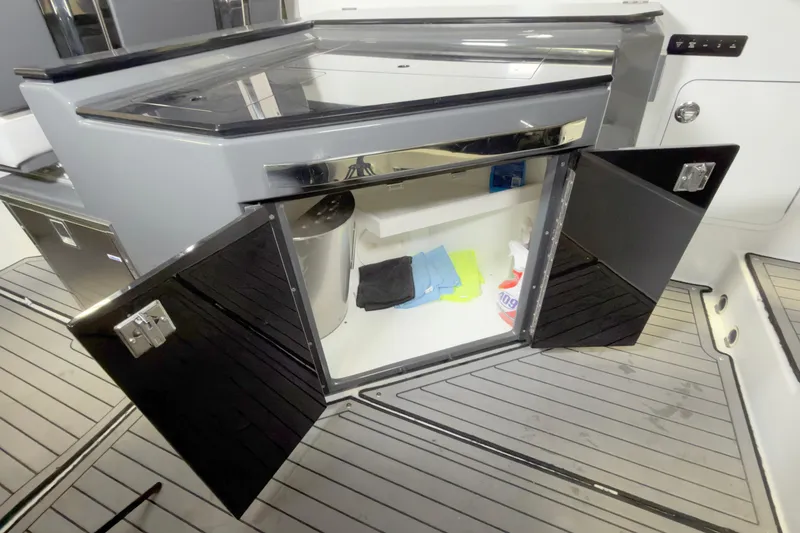 Slide: The Image of 2021 Cobalt A36BR boat interior storage compartment with open doors, revealing cleaning supplies. - 24