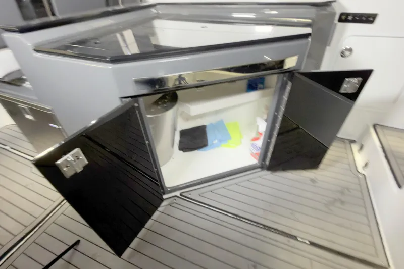 Slide: The Image of Open storage compartment on 2021 Cobalt A36BR boat with cleaning supplies inside. - 25