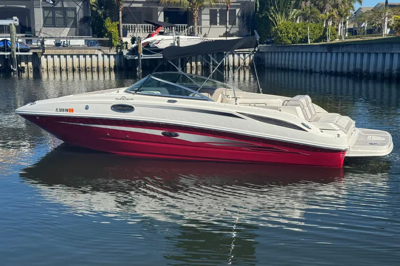 The Image of 2011 Sea Ray 260 Bow Rider boat with red hull, docked in calm waters. - 1