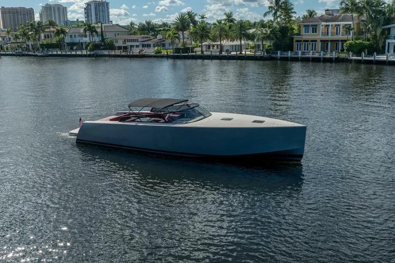 Slide: The Image of 2016 VanDutch 55 yacht cruising on a sunny waterfront with palm trees and luxury homes. - 2