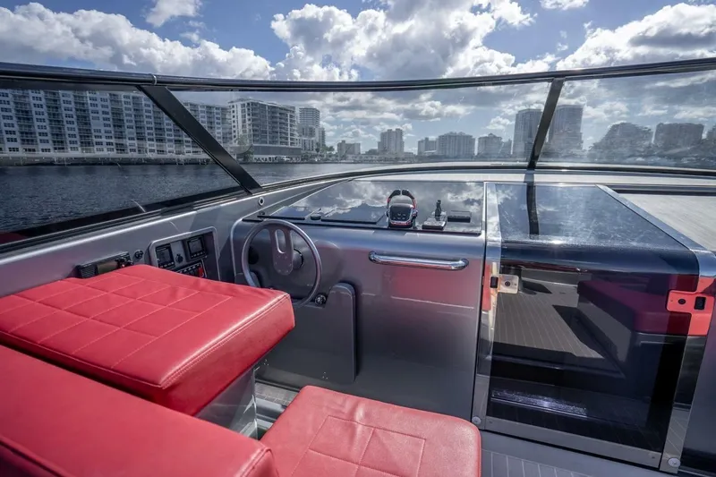 Slide: The Image of 2016 VanDutch 55 yacht cockpit with red seats, sleek dashboard, and city skyline view. - 8