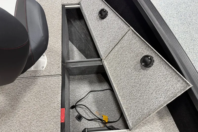 Slide: The Image of 2023 Alumacraft Competitor 185 Tiller storage compartment with open hatch and visible wiring. - 11