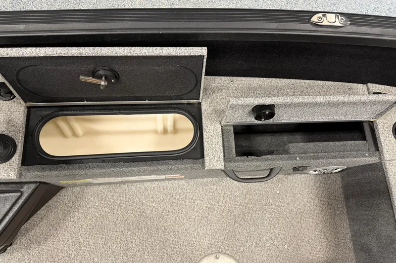 Slide: The Image of 2023 Alumacraft Competitor 185 Tiller boat storage compartments, open and empty, with carpeted interior. - 13