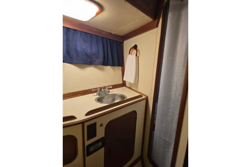 Slide: The Image of 1982 Irwin 52 yacht bathroom with sink, towel, and blue curtain. - 23