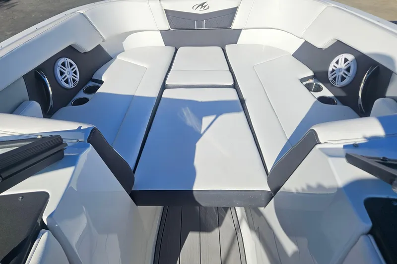 Slide: The Image of 2022 Monterey M-225 boat interior with white seating, cup holders, and speakers. - 12