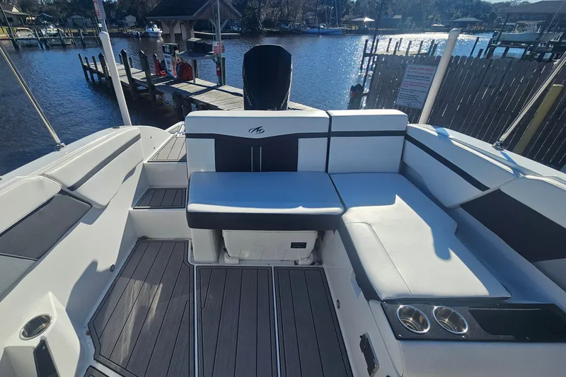 Slide: The Image of 2022 Monterey M-225 boat interior with seating, docked by a scenic waterfront. - 18