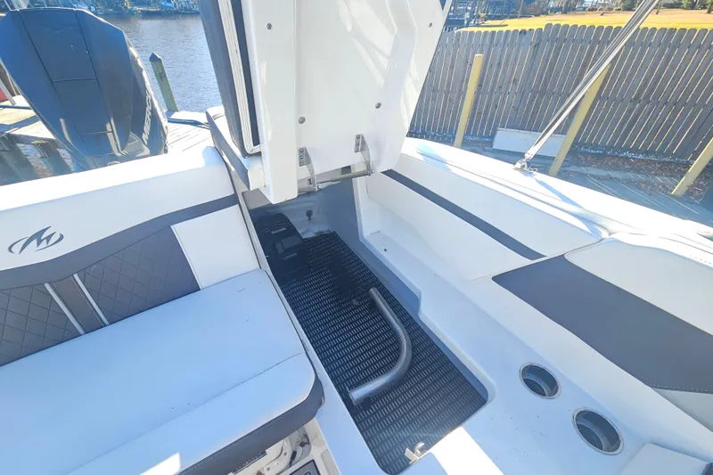 Slide: The Image of 2022 Monterey M-225 boat interior with seating and storage area, docked by the water. - 19