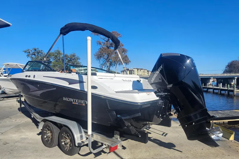 Slide: The Image of 2022 Monterey M-225 boat on trailer by waterfront, featuring Mercury outboard motor. - 3