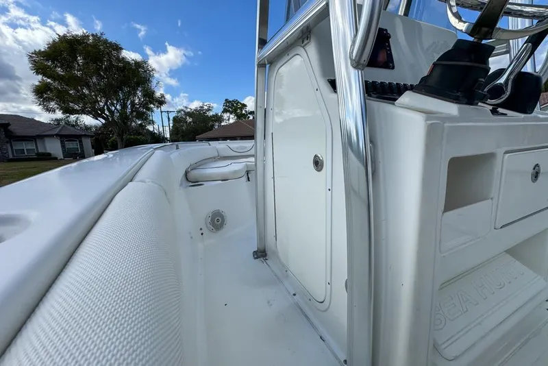 Slide: The Image of 2016 Sea Hunt Ultra 211 boat interior with console and seating, under a clear blue sky. - 103
